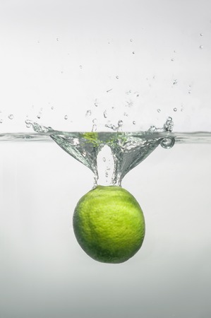 Ripe tempting lime dipped into the water with little air bubblesの写真素材