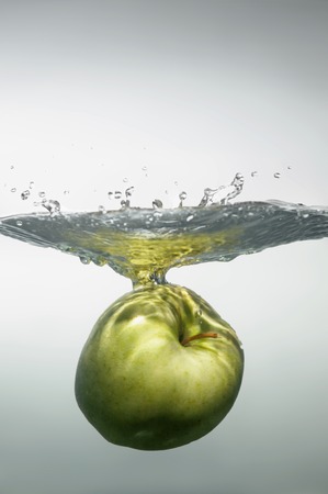 Tempting green apple under the water close to surfaceの写真素材