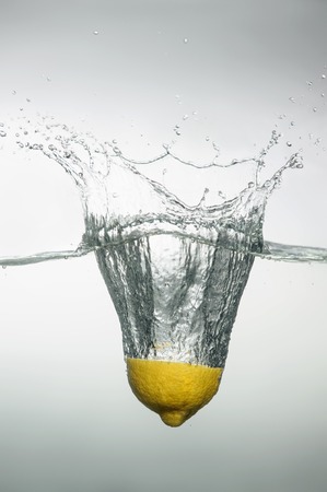 Tempting slice of lemon dropped into the water with splash and bubblesの写真素材