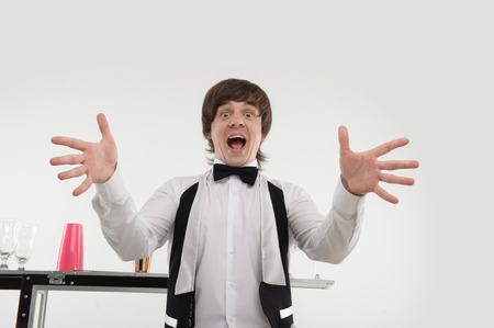 Half-length portrait of dark-haired barman standing behind the bar counter and meeting his friendsの写真素材
