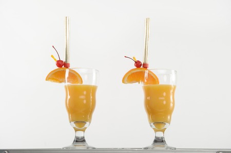 Two very delicious cocktails with slice of orange and cherry on it preparing for youの写真素材