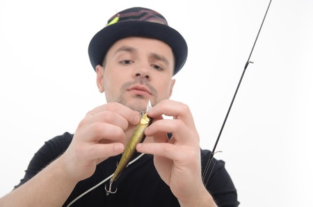 Half-length portrait of prudent fisherman moving the bait up to the fishing rod  Isolated on white backgroundの写真素材