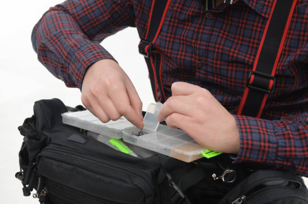 Man wearing nice checked shirt taking out fishing baits from the plastic box  Close upの写真素材