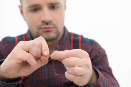 Selected focus on the fishing bait in the hands of man, wearing checked colorful shirt on backgroundの写真素材