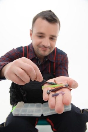 Selected focus on the different colorful flies in the hands of smiling man wearing checked shirt on backgroundの写真素材