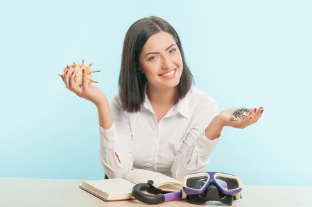 Beautiful smiling woman wearing white blouse holding two nice seashells in both her hands 