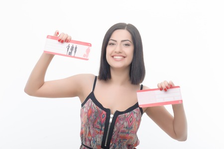 Half-length portrait of very attractive dark-haired girl smiling and showing her airline tickets  Horizontal photo  Isolated on white background の写真素材