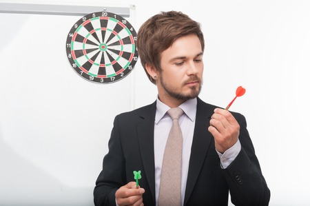 Handsome dark-haired bearded man wearing perfect jacket standing near the target holding colorful...