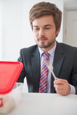 Handsome young businessman wearing great black suit and colorful tie intended to have a lunch in the...