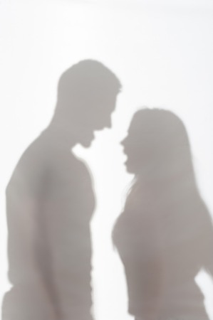 Silhouette of man and woman standing on white background and quarrelling の写真素材