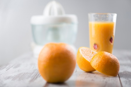 Selective focus on the orange juice and halves of orange standing on the table  Juicer on backgroundの写真素材