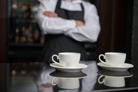 Selective focus on two white cups of coffee standing on the bar counter  Professional barista with...