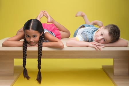 Half-length portrait of pretty dark-haired smiling little girl with little fair-haired boy wearing T-shirt の写真素材