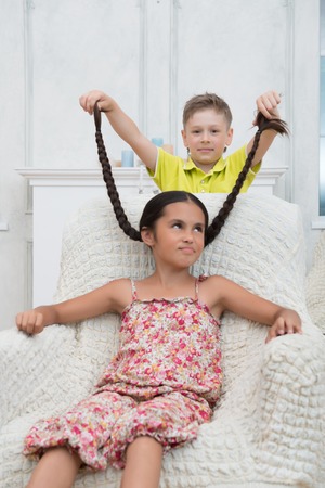 Portrait of pretty dark-haired angry little girl wearing nice colored dress sitting in the...