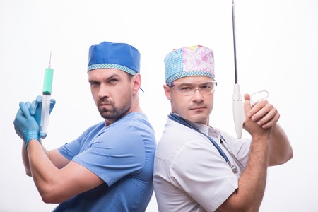 Half-length portrait of two funny doctors wearing medical dress standing back to each other holding...