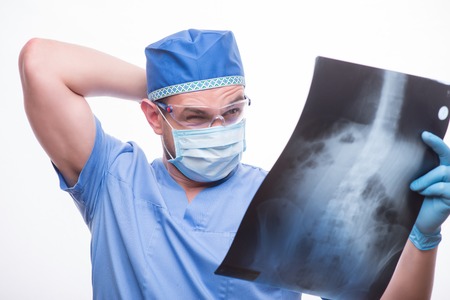 Half-length portrait of the doctor wearing blue medical dress hesitating looking at the X-ray...
