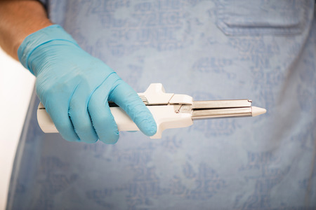 Selective focus on the surgical tool in the hands of the doctor wearing blue disposable gloves and medical dressの写真素材