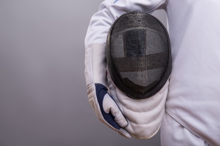 Half-length portrait of the girl wearing white fencing costume holding the fencing mask. の写真素材