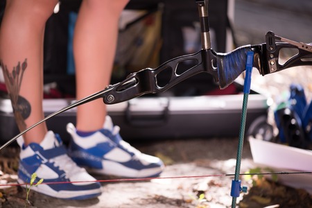 Selective focus on the great bow lying on the ground near the legs wearing nice sneakers on...