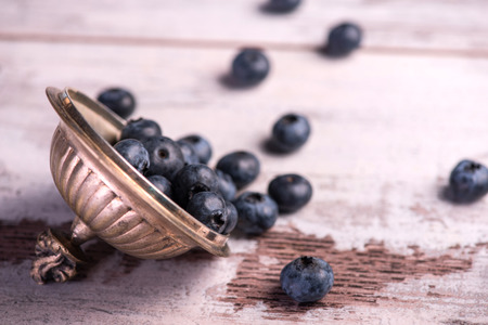 Selective focus on the copper top with little blackberries in it lying on the wooden tableの写真素材