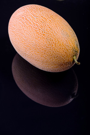 Wonderful ripe melon lying on the black vitreous surfaceの写真素材