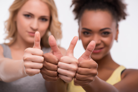 Selective focus on the thumbs of two friends making fun smiling on backgroundの写真素材