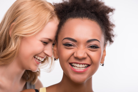 Half-length portrait of two young pretty smiling women satisfied with their life having a fun. Isolated on white backgroundの写真素材