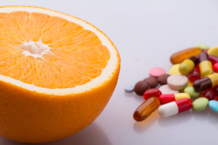 Selective focus on the juicy tempting orange. A heap of pills on backgroundの写真素材