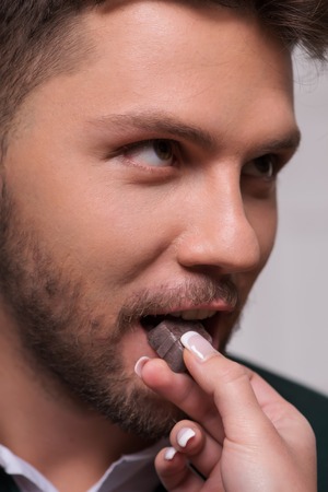 Selective focus on the man wearing green sweater looking at his girlfriend feeding him chocolate pralineの写真素材
