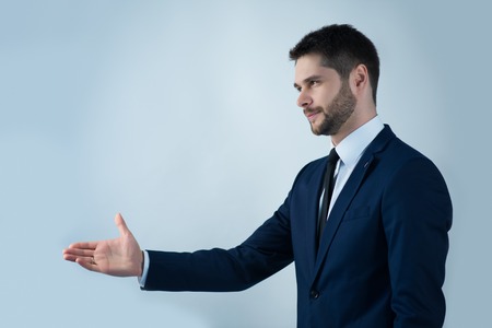 Half-length portrait of handsome young bearded man wearing white shirt tie and blue jacket standing aside wanted to greet with someone. Isolated on white backgroundの写真素材