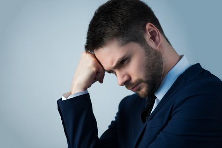Half-length portrait of handsome young bearded thoughtful man wearing white shirt tie and blue jacket standing aside wanted to remember something. Isolated on white backgroundの写真素材