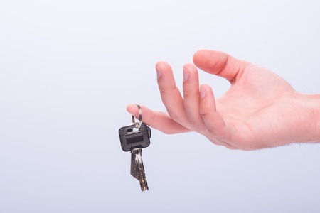 Hands of woman giving someone keys isolated on white background.  Concept of new lifeの写真素材