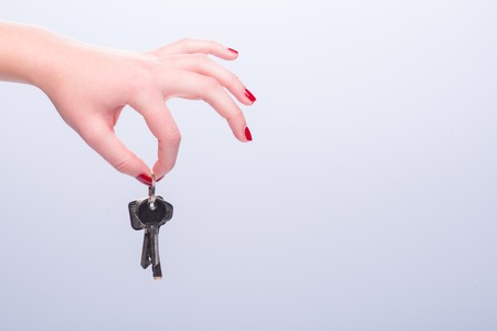 Hands of woman giving someone keys isolated on white background.  Concept of new lifeの写真素材