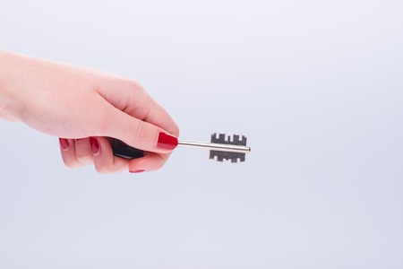 Hands of woman wanted to unlock something with the help of key isolated on white background.の写真素材