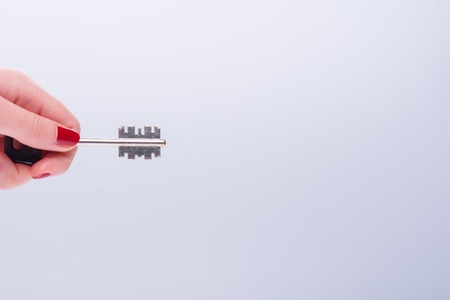 Hands of woman wanted to unlock something with the help of key isolated on white background.の写真素材