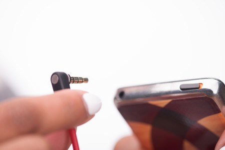 Selective focus on the hand of the girl wanted to connect her earphones to the mp3 playerの写真素材