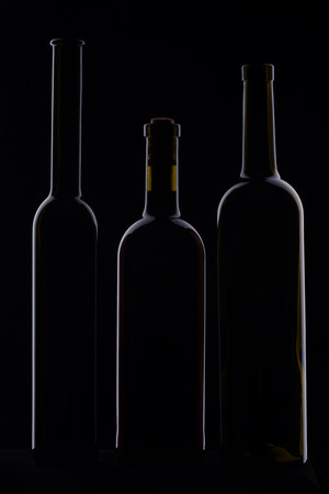 Three bottles of wine standing isolated on the dark backgroundの写真素材