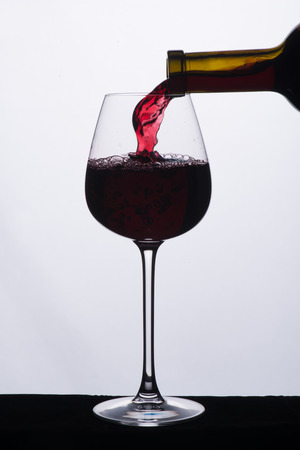 Elegant glass is filled with the red wine isolated on the white backgroundの写真素材
