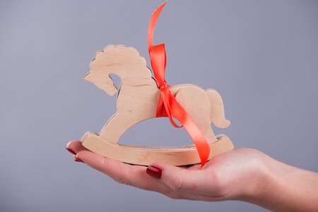 Little toy horse with red band lying in the hands of the womanの写真素材