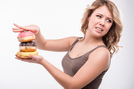 Closeup portrait of young attractive woman rejecting doughnuts isolated on white background, diet conceptの写真素材