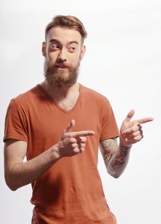 I choose you.  Handsome tattooed bearded man wearing orange tshirt and pointing with two fingers away while standing against white backgroundの写真素材