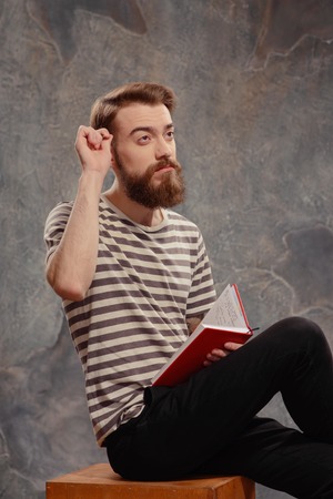 Young and creatively independent.  Portrait of young bearded tattooed man in a striped longsleeve...