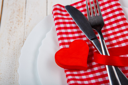 The perfect romantic dinner. Closeup of wooden table served with romantic heart shape decor and...