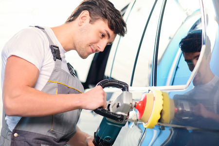 Passionate about cars. Portrait of a handsome smiling car mechanic polishing the luxury car with a...