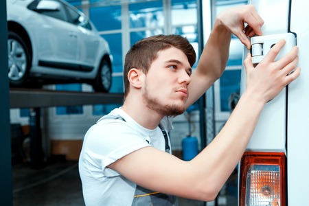 Double- check the door. Portrait of a concentrated handsome mechanic in uniform checking the door of...
