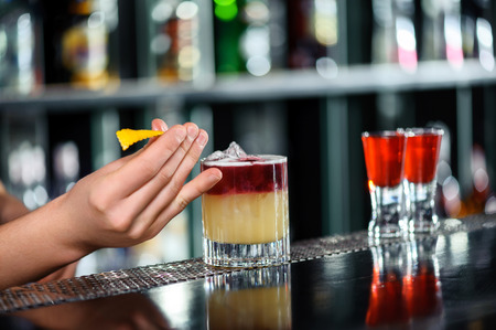 Stylish decoration. Close-up of a bartender placing a slice of citron onto the cocktail in a glassの写真素材