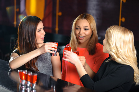 Cheers to friendship. Three beautiful women entertaining in the bar and toasting shotsの写真素材
