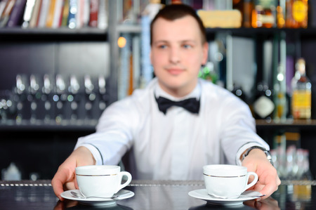 Tasty coffee. Close-up of cups of coffee at the car counter with barman in bow time blurred on the backgroundの写真素材