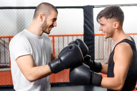 Friendly game. Two boxers joyfully laugh standing in a fighting cage