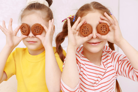 New eyes. Two funny little girls posing with cookies putting them to eyesの写真素材